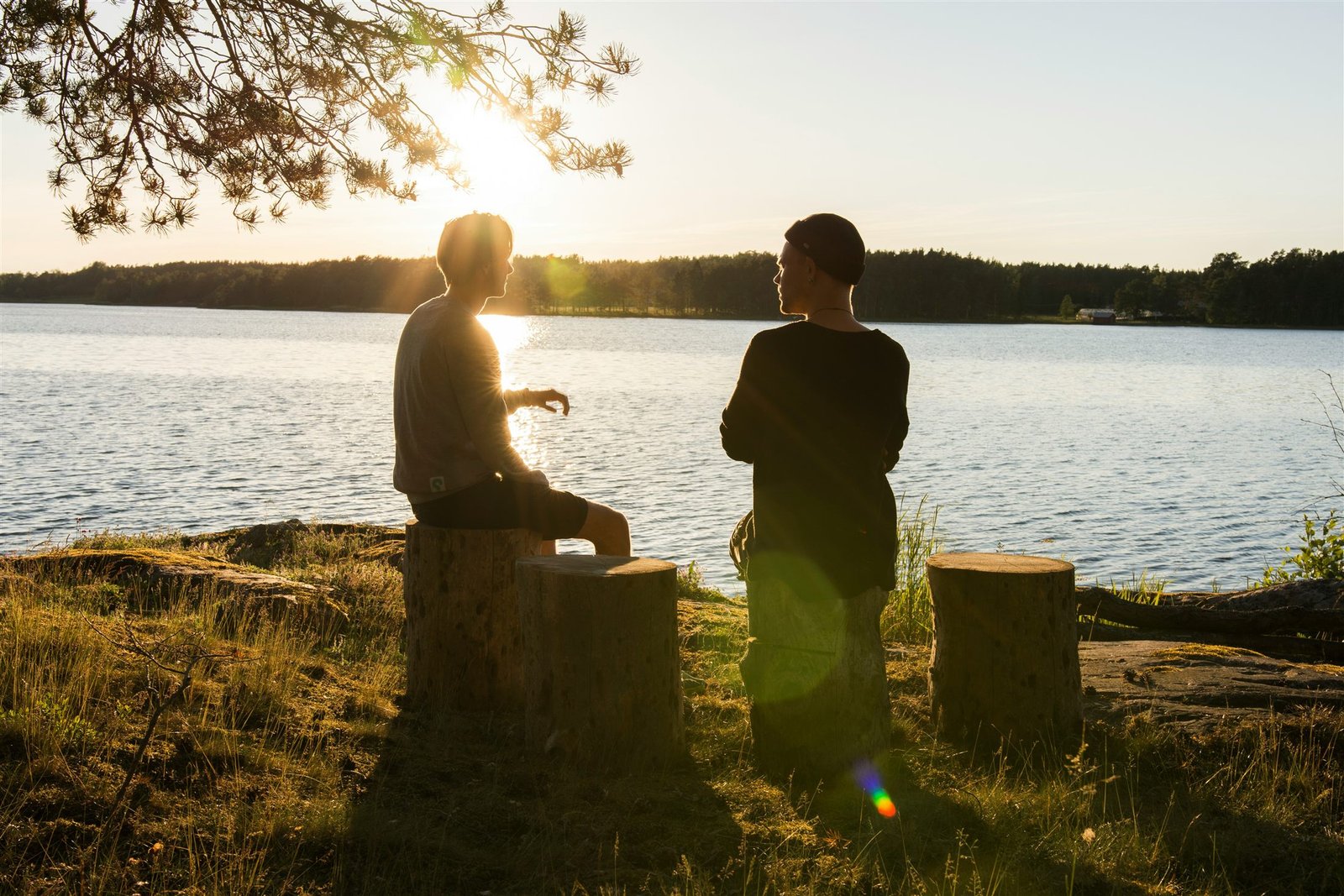 Dos personas conversando junto a un lago al atardecer
